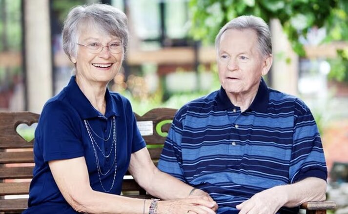 Husband and wife sitting together on a bench outdoors at Traditions of Mount Vernon in Mount Vernon, Ohio.